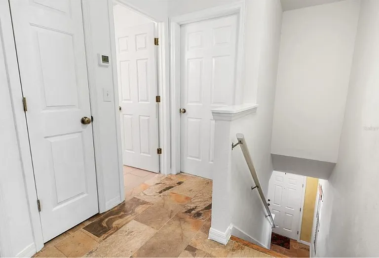 Landing at top of stairs (open door is the full bath, right door is primary bedroom, left door is closet