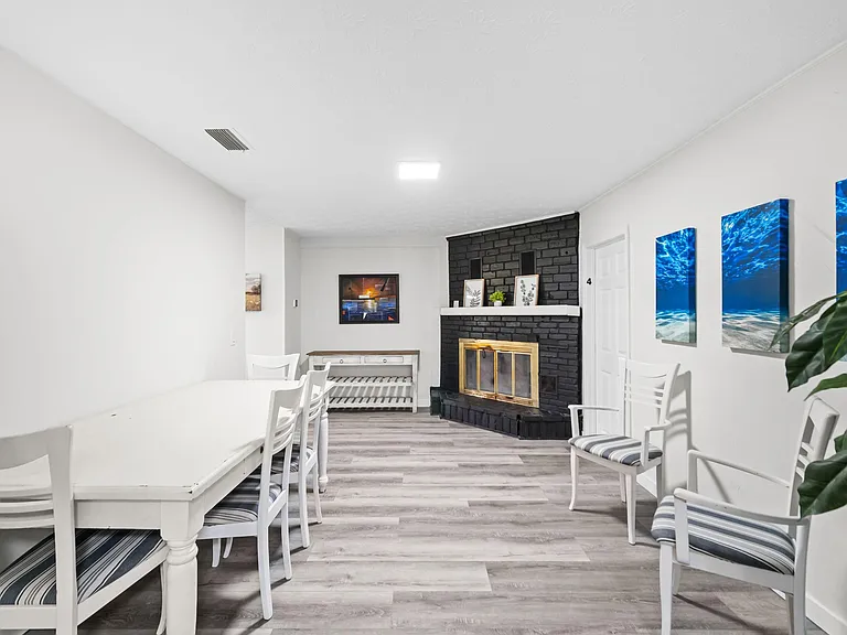 Dining area with a full table and chairs, easy-care flooring, and a statement brick fireplace for added character.