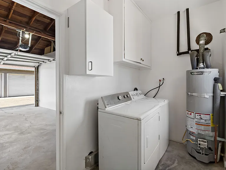 Separate laundry room with washer and dryer in the back of the garage