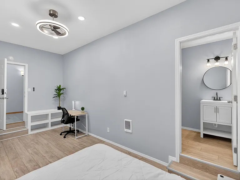 Private bedroom with wood-look flooring, a built-in bench nook and desk area, plus convenient access to a nearby bath.