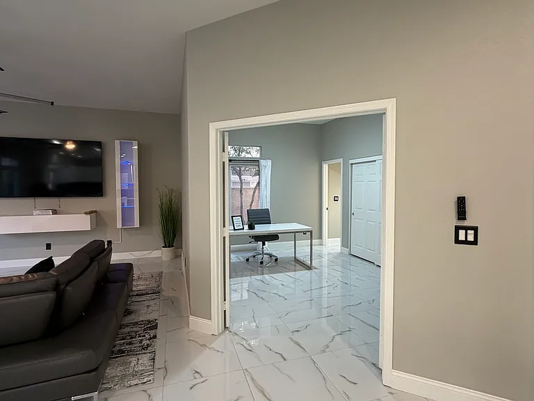 Furnished living and dining area with double-door access to a private office and en-suite bath, offering a flexible layout.