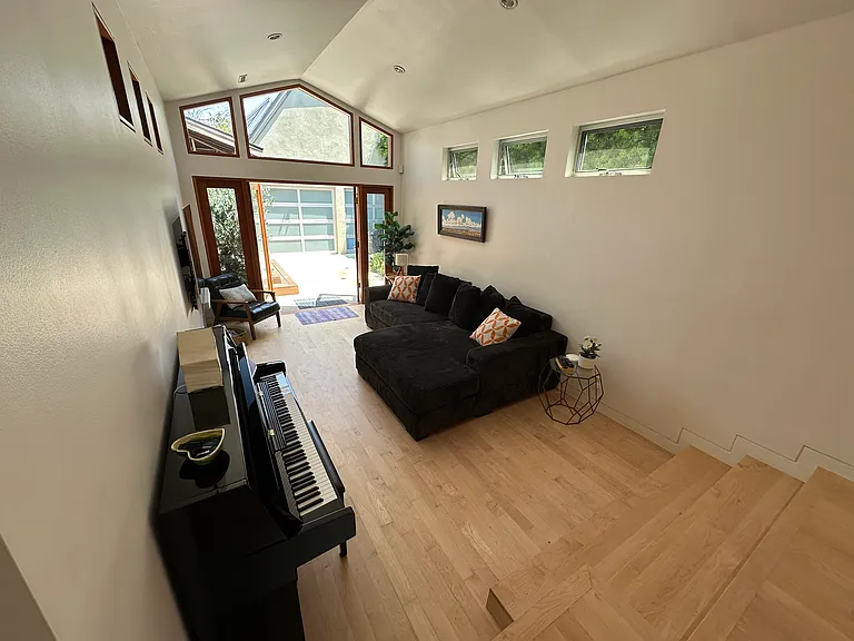 Open plan high ceiling living area with piano, 60" screen, Sonos, etc - french doors to backyard