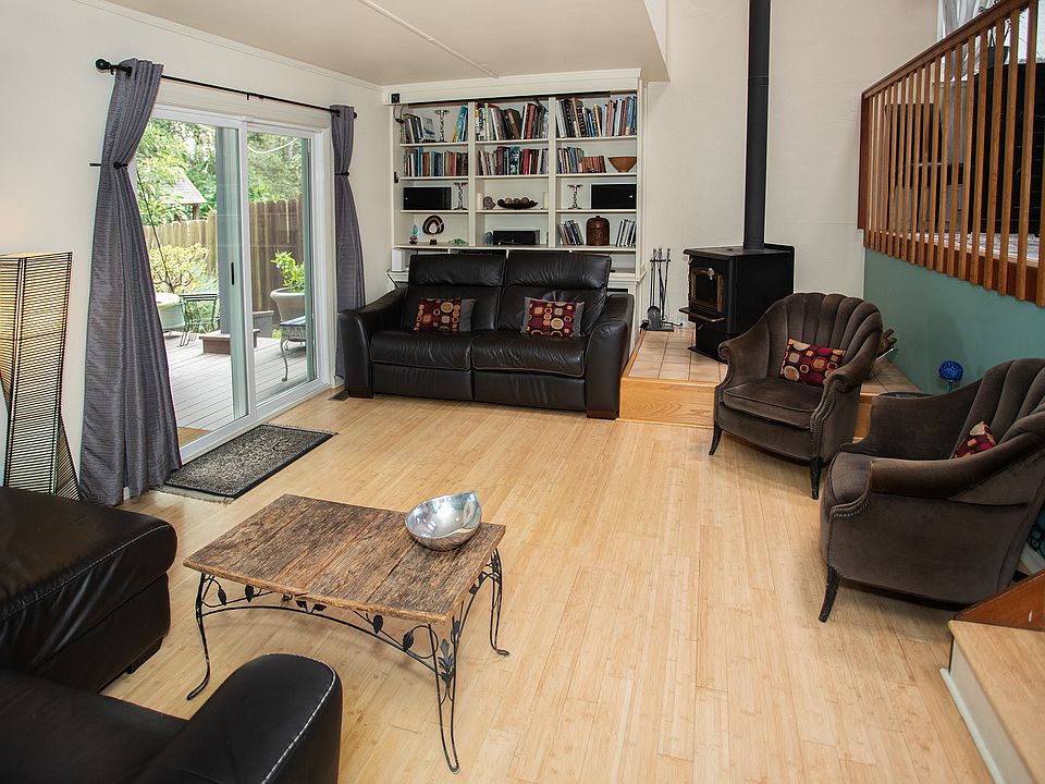 Living room with projector screen built into bookcase, wood burning stove, recliner couches, and access to deck.