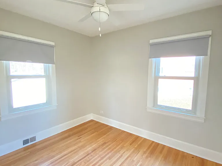 Bedroom 2 with two windows, hardwood floors and ceiling fan