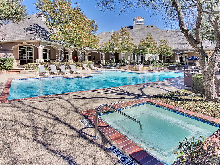 Stunning, tree-lined swimming pool and hot tub with tanning deck and lounge seating