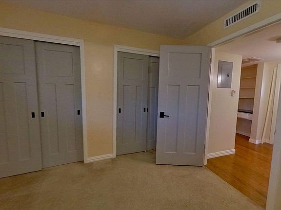 Guest bedroom with 2 closets, with view of hallway.