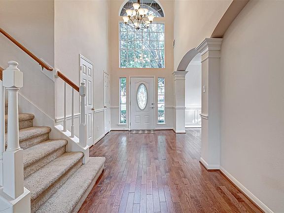 This beautiful foyer features a soaring ceiling and arched window above front door.
