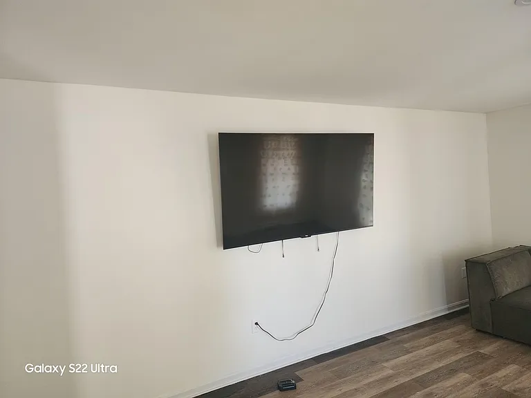 Living area with durable wood-look flooring and a wall-mounted TV, offering space for comfortable seating and relaxing.