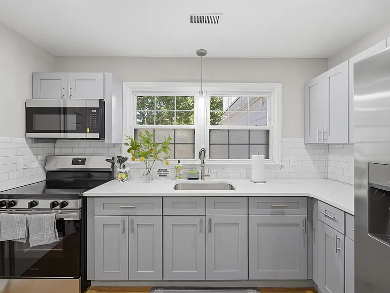 Updated kitchen with ample cabinetry, generous counter space, stainless appliances, and a window over the sink.