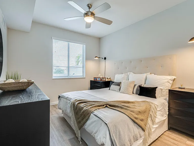 Bedroom Featuring Ceiling Fan, Tufted Headboard, and Window with Blinds
