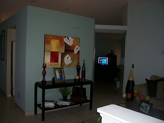 Standing at the front door to the right.