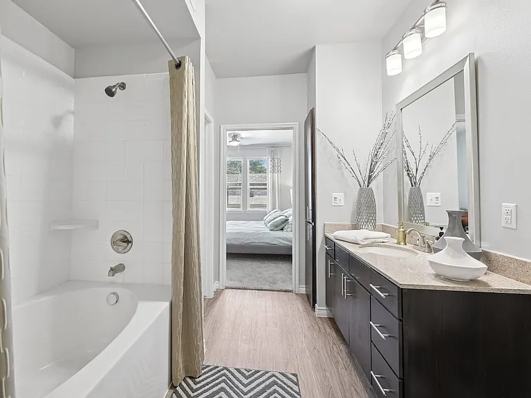 Bath with dark cabinetry, beige speckled granite countertops, and hard surface flooring
