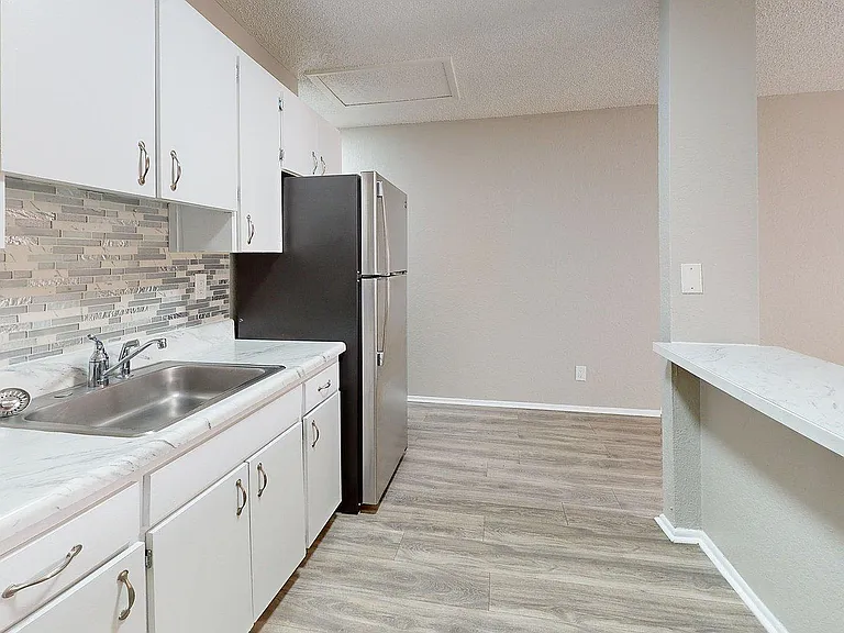 Modern kitchen with sleek stainless steel appliances, elegant white cabinetry, and stylish tile backsplash.