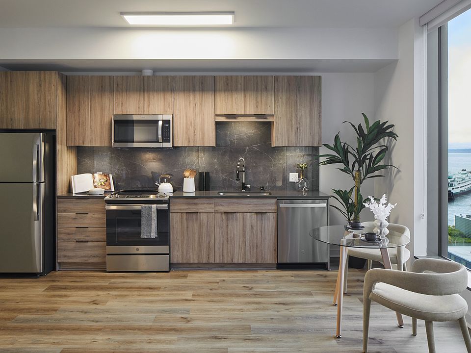 Apartment kitchen with stainless steel appliances, quartz countertops and wood-style flooring.