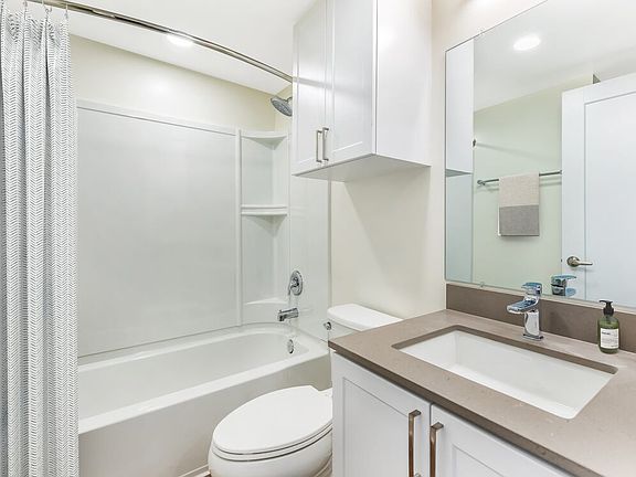 Renovated Package II bath with light grey quartz countertop, white shaker cabinetry, and hard surface flooring