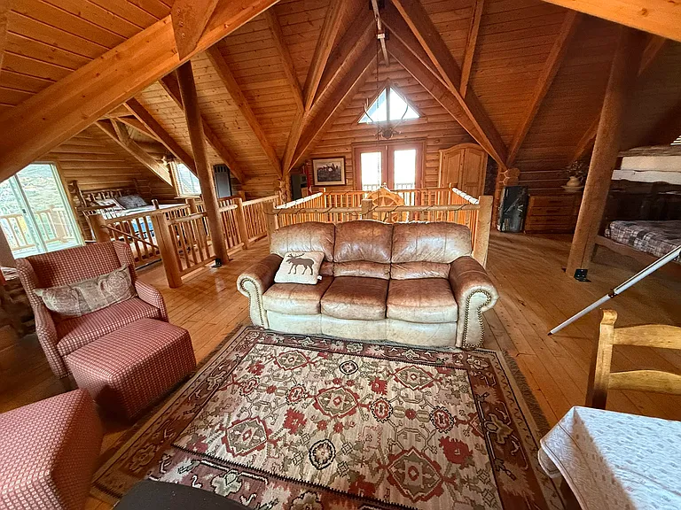 View of top floor sitting area (sofa, arm chairs, table) looking at French doors to balcony.