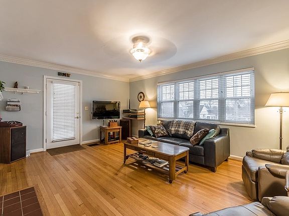 Living room with hard wood floors, wood burning fire place, and crown moulding
