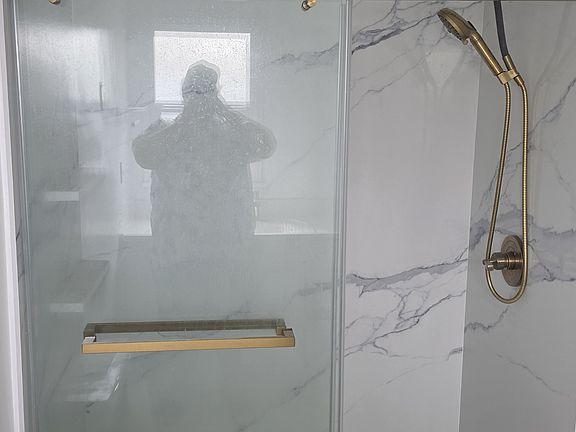 New shower with sliding glass doors and stone walls