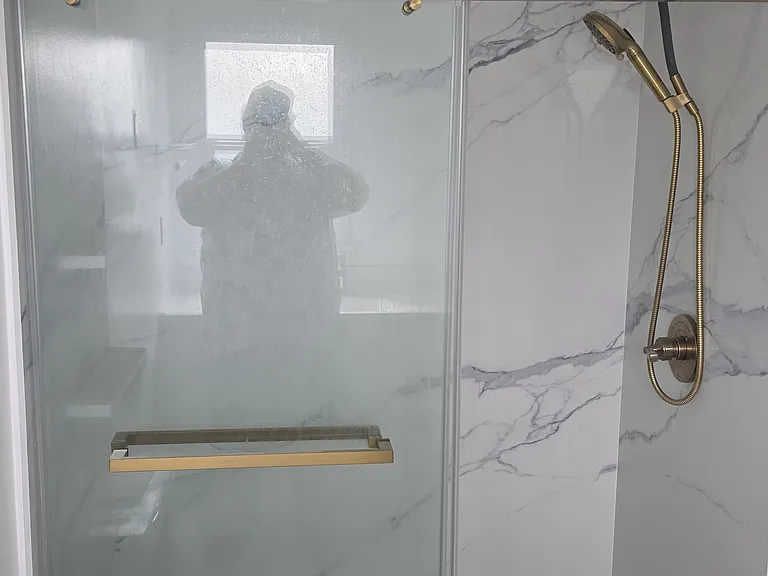 New shower with sliding glass doors and stone walls