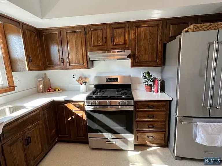 Beautiful kitchen countertop with new range, large fridge and dishwasher. Area for kitchen table to the right of this picture. Ample space.