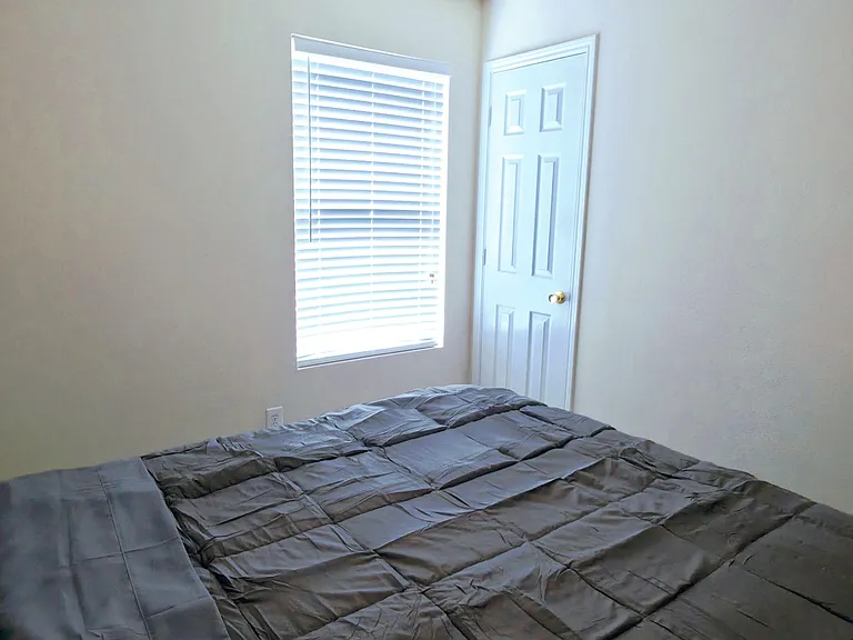 Private bedroom featuring a ceiling fan, neutral walls, and a window with blinds for light control and privacy.