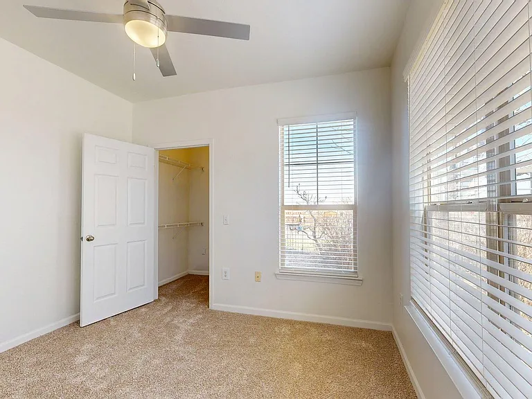 Spacious apartment bedroom with plush carpet flooring.