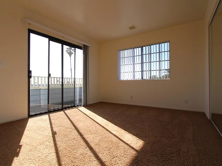 Bedroom with window and sliding glass door to ocean facing balcony