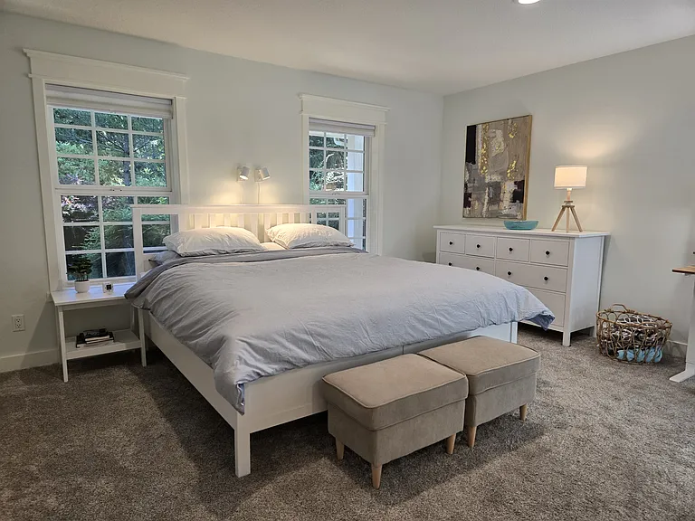Master suite on the first floor featuring king bed, a 65" TV, and a sit-stand workstation