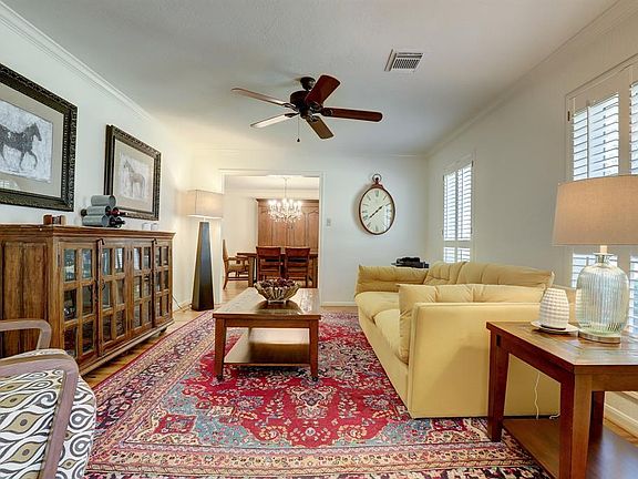 The formal living room provides a genteel space for quiet conversation or entertaining, and features a ceiling fan, crown moulding, and plantation shutters.