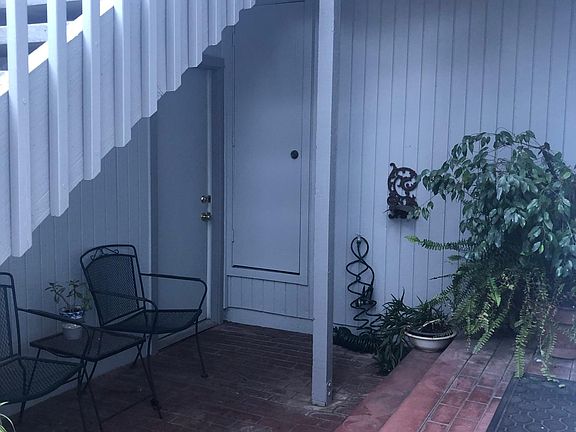 Front patio with garage door next to chair. Water heater closet in photo on the wall next to pole