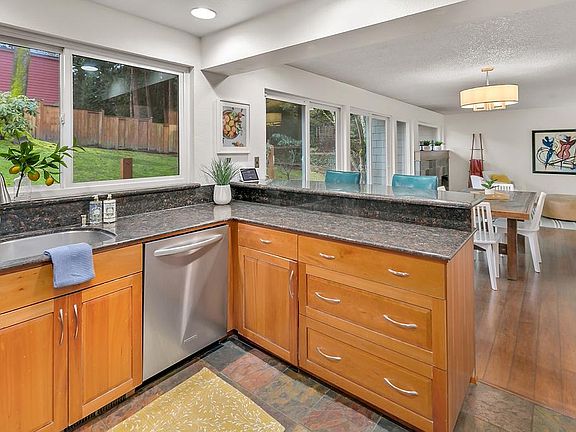 Kitchen looks out over dining area and living room. Walls of windows provide an abundance of light.
