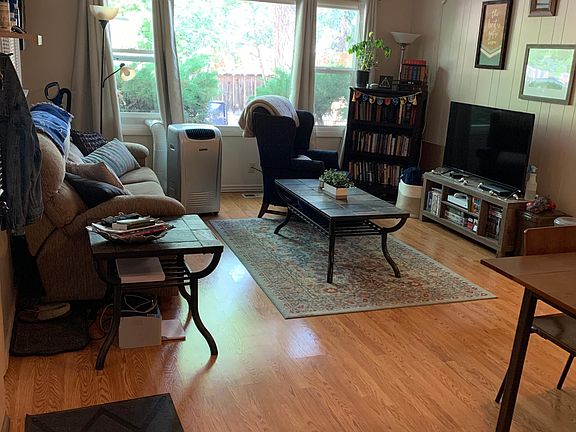 Kitchen looking into living area with fenced backyard visible through picture window.