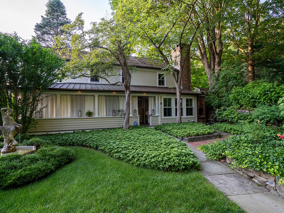 Side view of all season porch and stone walk way surrounded by lush landscaping and featuring a delicate fountain