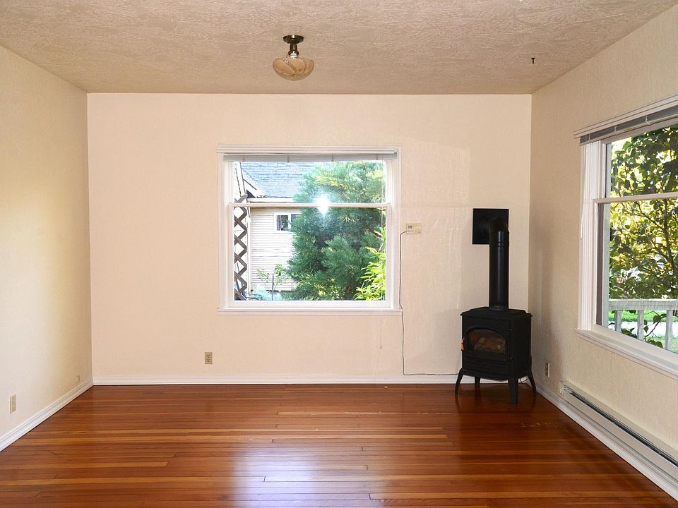 Living room unfurnished. The gas fireplace is in the corner. You can see flames through the glass in the front when you have it on. The thermostat to control the fireplace is on the wall to the left. There is now also a ductless heater above the window.