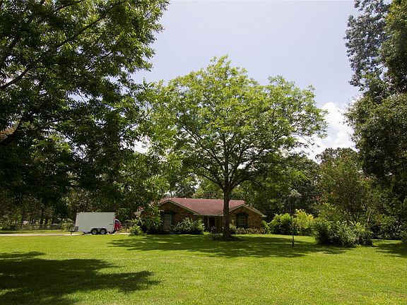 Large front yard with mature trees, colorful flowering trees, and ample fruit trees.