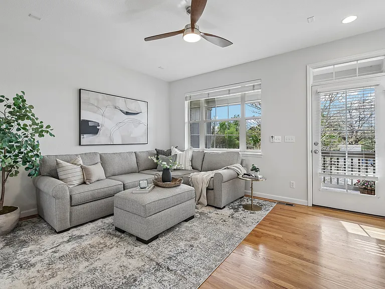 Open floor plan filled with natural light, ceiling fan, and hardwood floors.