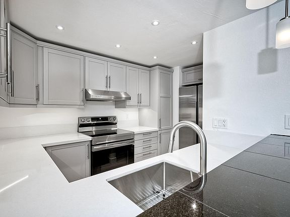 Brand new kitchen with stainless steel appliances and under cabinet lighting.