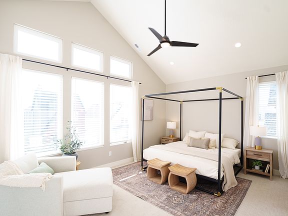 Bright bedroom from the Contempo Collection with a four-poster bed, two wooden stools at the foot, n