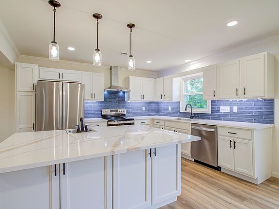 Gorgeous new light and bright kitchen with pendant lighting, decorative tile backsplash, and stainless steel appliances.