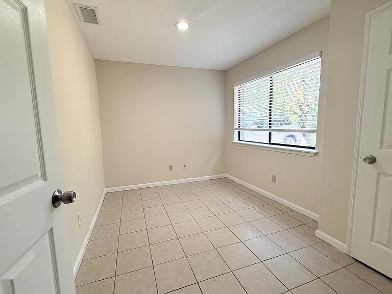 Comfortable secondary bedroom featuring tile flooring, large window, and plenty of space for a bedroom set or home office