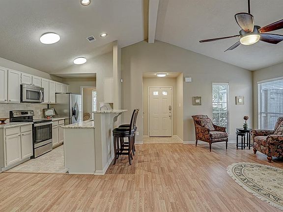 New honey oak laminate flooring, abundant natural light and vaulted ceiling accentuate open-concept