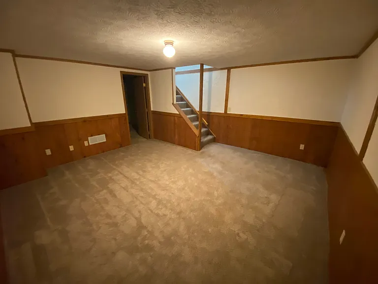 Finished basement looking at door to unfinished basement and stairs to the first floor