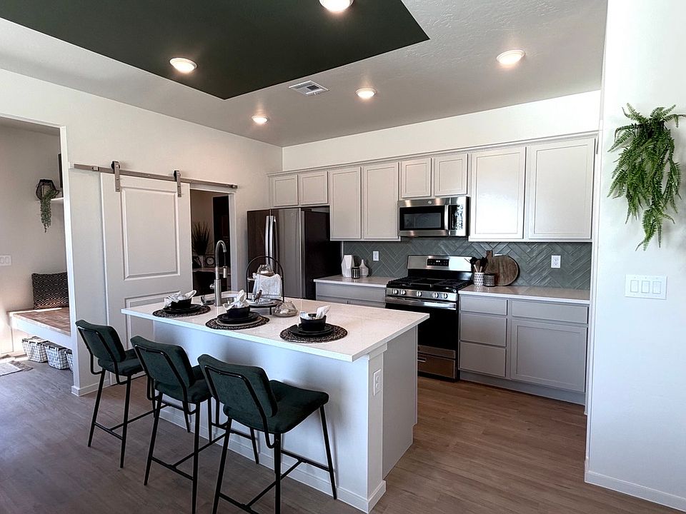 Modern kitchen with white cabinets, stainless steel appliances, an island with three green barstools