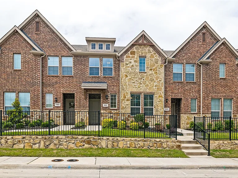 Welcome home to this beautiful townhome exterior featuring a brick and stone facade