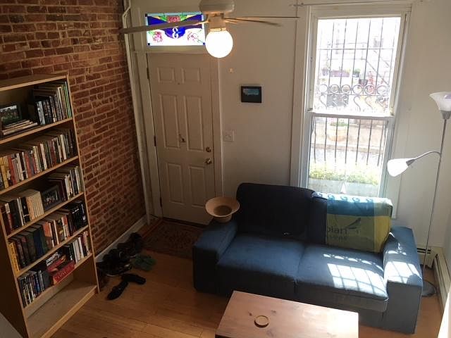 Living room (as furnished by previous tenant) with handmade stained glass and hand-forged ornamental wrought iron window guard, by Baltimore artists.