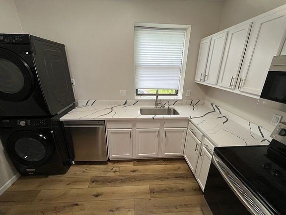 Kitchen with brand new countertops, cabinets, washer/dryer, and stainless steel appliances.