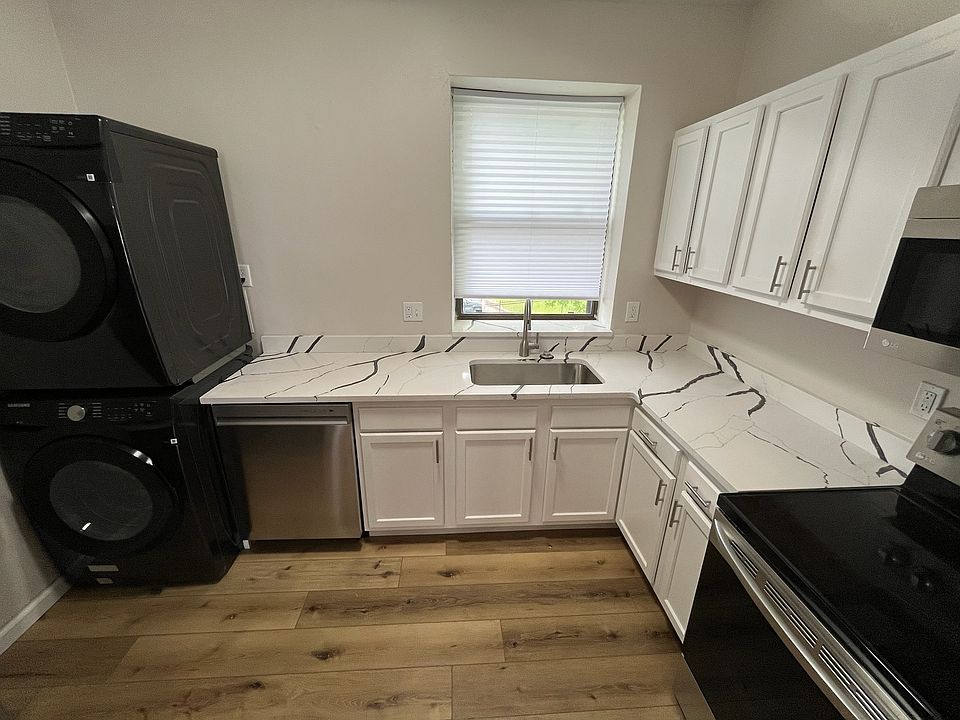 Kitchen with brand new countertops, cabinets, washer/dryer, and stainless steel appliances.