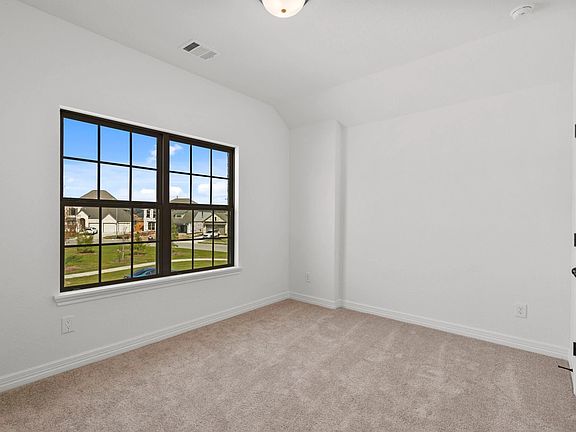 Fourth bedroom on the main level with large windows, plush carpet, and a spacious closet-comfortable