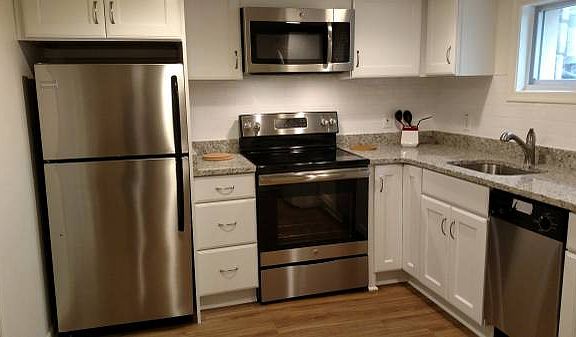 Renovated kitchen with granite countertops, dishwasher, disposal, stove, microwave and kitchen cart.
