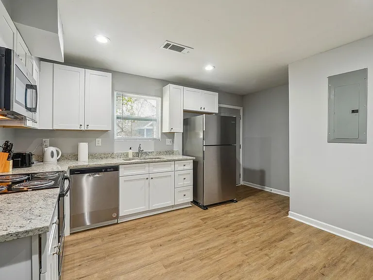 Kitchen features white cabinetry, granite-look counters, stainless appliances, and a window over the sink for easy meal prep.